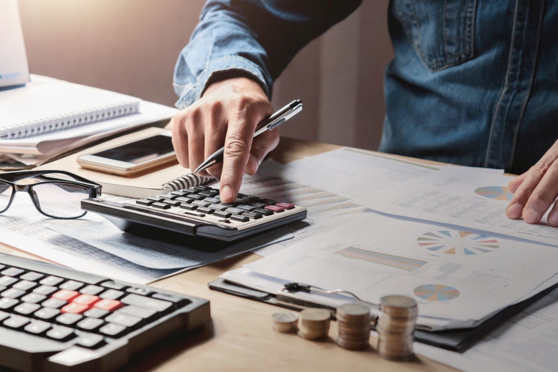 Mann am Tisch mit Taschenrechner und Bargeld